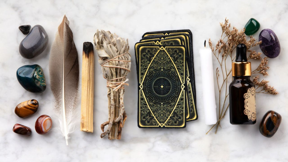 Image of crystals, feathers, palo santo and a tarot deck on a marble background.