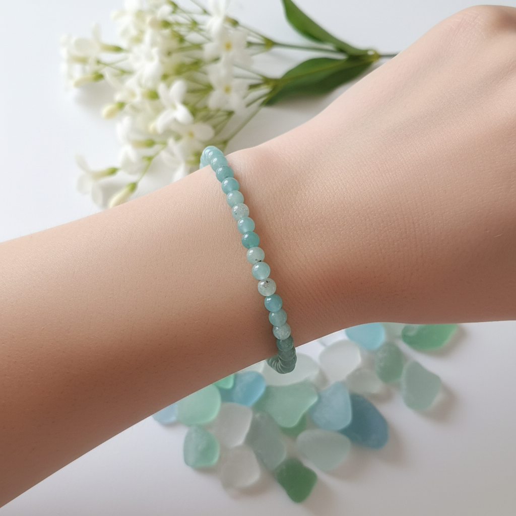 Amazonite 4mm bracelet worn on wrist in soft natural light with white flowers and sea glass in background — Prana Blessings