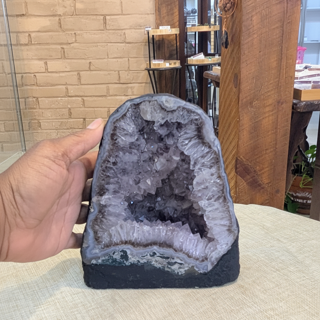 AC3 natural Amethyst Cathedral with violet crystal interior held in hand to show approximate scale