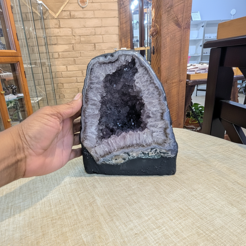 AC2 natural Amethyst Cathedral with violet crystal interior held in hand to show approximate scale