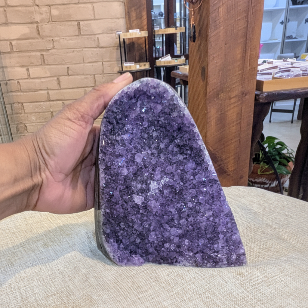 Extra-large Uruguayan Amethyst cluster No. 6 with polished cut base held in hand to show approximate scale