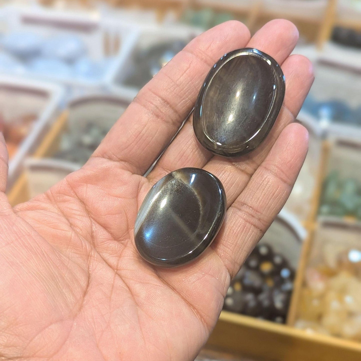 Two black onyx soothing stones also called worry stones, in the palm of a hand. 