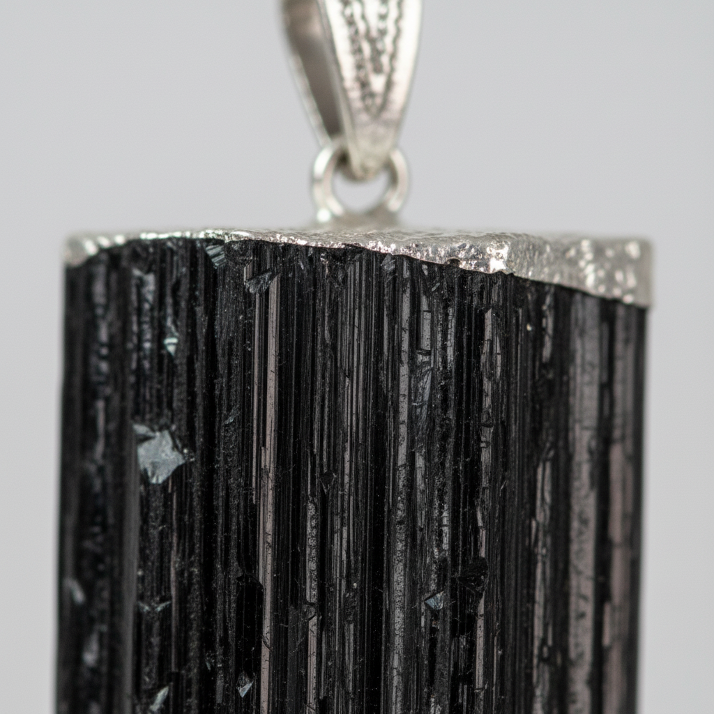 Close-up of Black Tourmaline pendant showing natural rough striations and metal cap