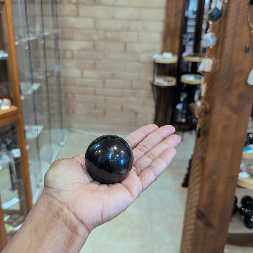Polished 40mm Black Tourmaline sphere held in hand to show approximate scale