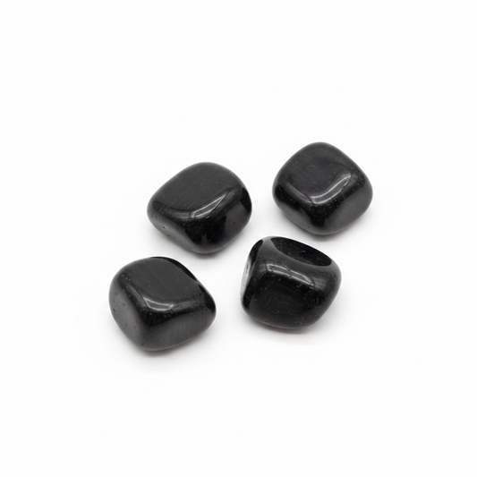 Polished black tourmaline tumbled stones arranged on a clean white background.