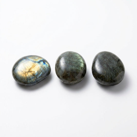 Three polished labradorite stones in oval shapes, arranged horizontally on a clean white background. The stones display natural iridescent flashes of gold, blue, and green.