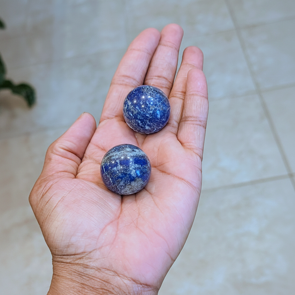 Mini polished deep blue Lapis Lazuli spheres held in hand to show approximate scale