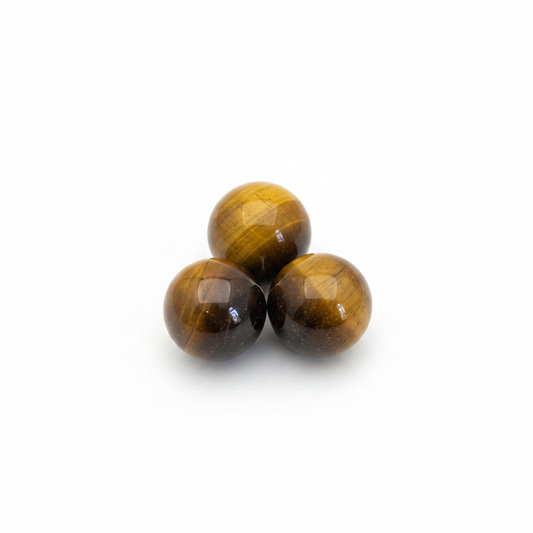 Mini polished golden-brown Tiger’s Eye spheres on a clean light background