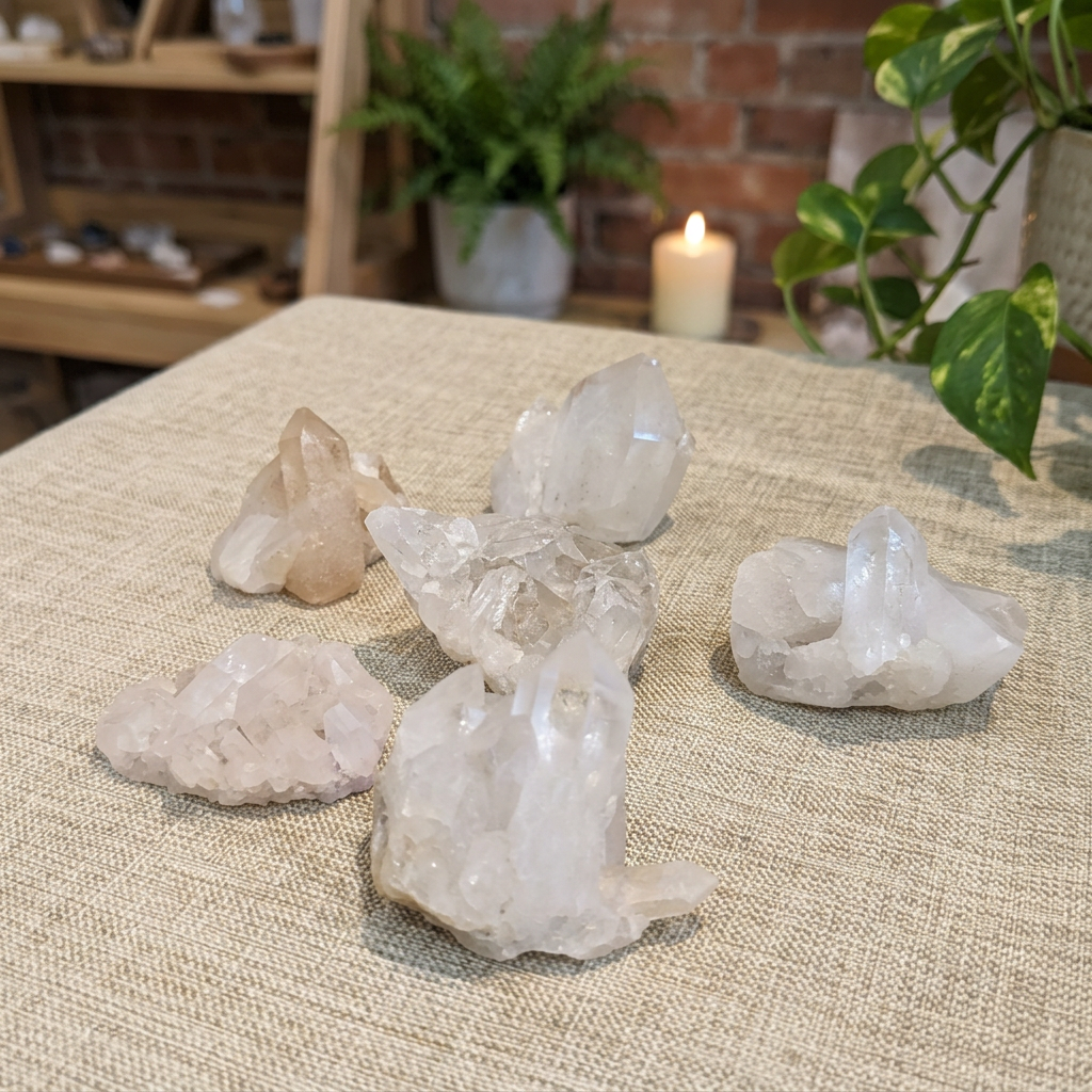 Large Clear Quartz clusters arranged on warm linen beside a candle