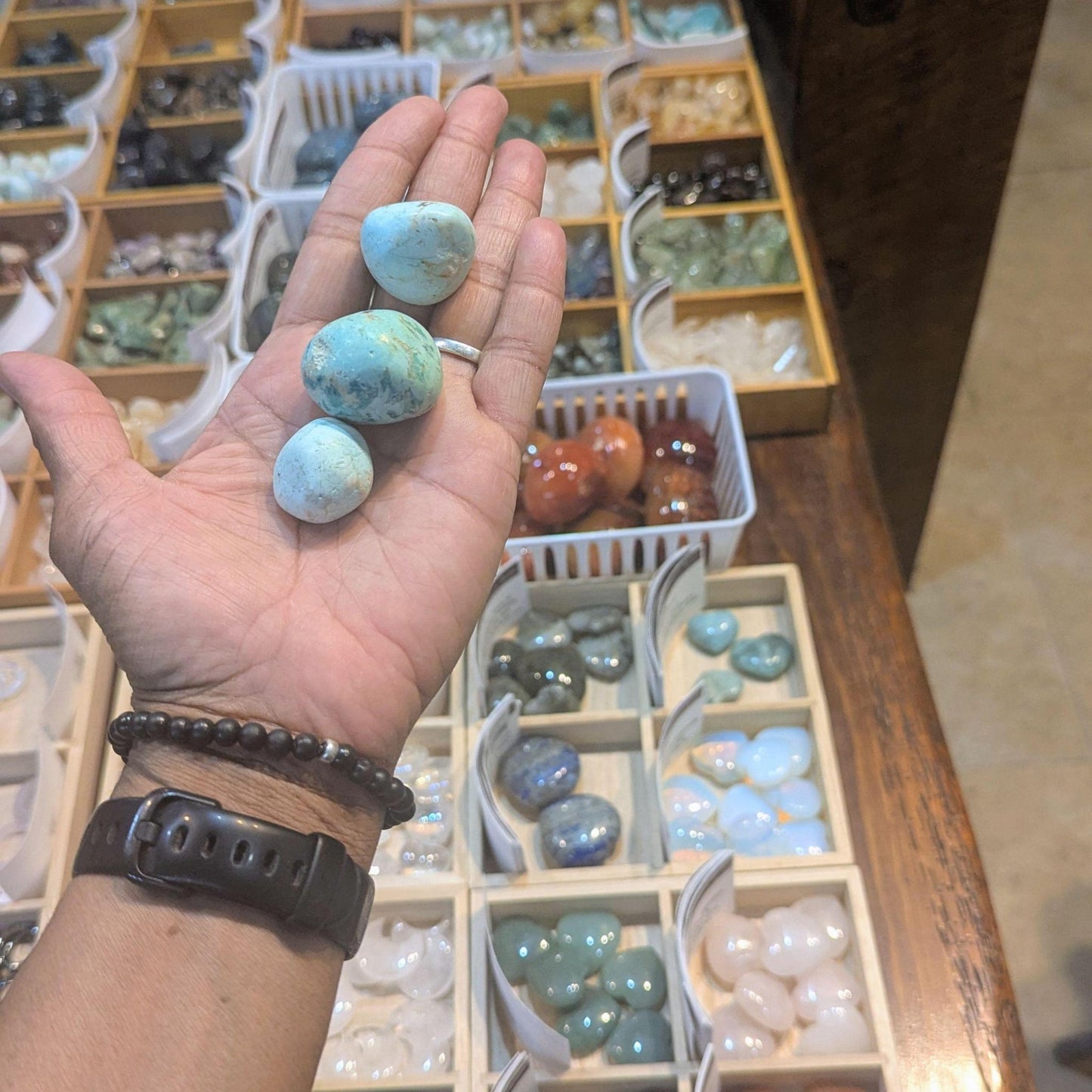 Multiple tumbled Peruvian turquoise stones in a hand, showing their natural teal and aqua colors with distinctive matrix markings